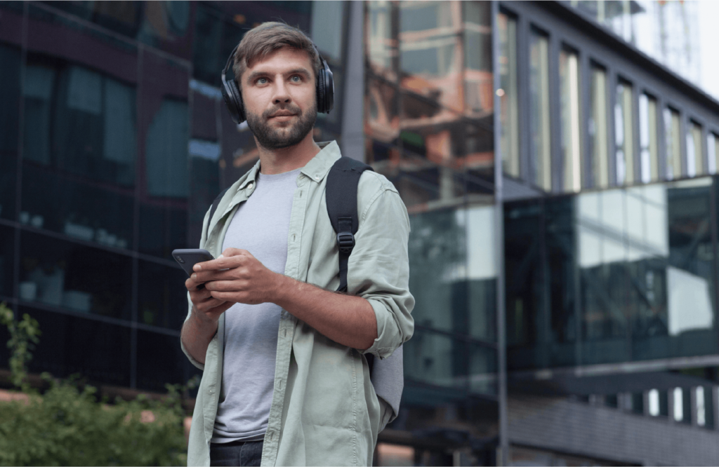 イメージ画像　スマートフォンを頼りに街を歩く、ヘッドフォンを着用した男性